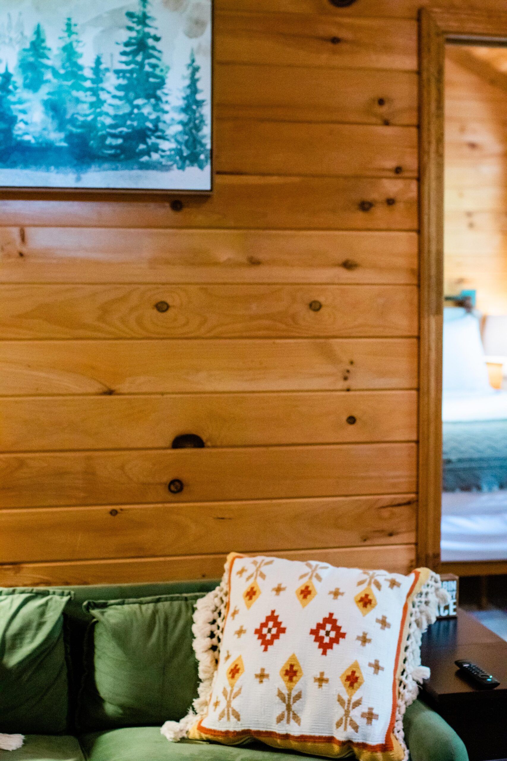 A couch with a pillow on it in front of a wooden wall.