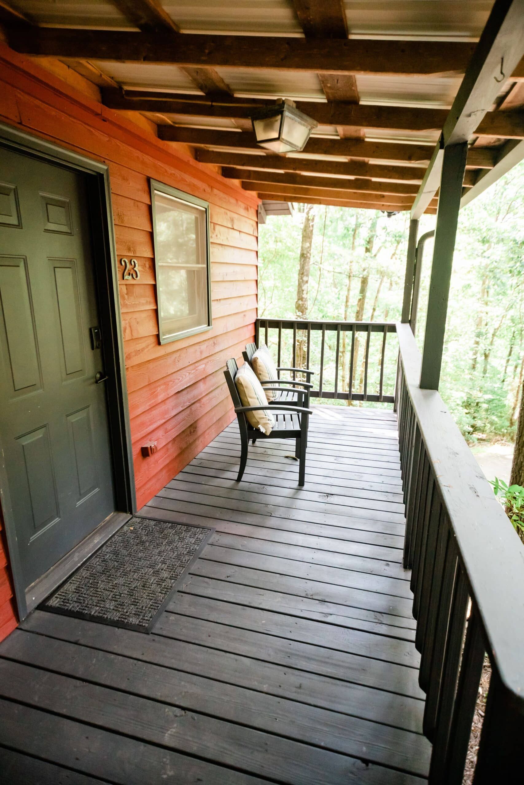 A wooden porch with a bench and chairs on it