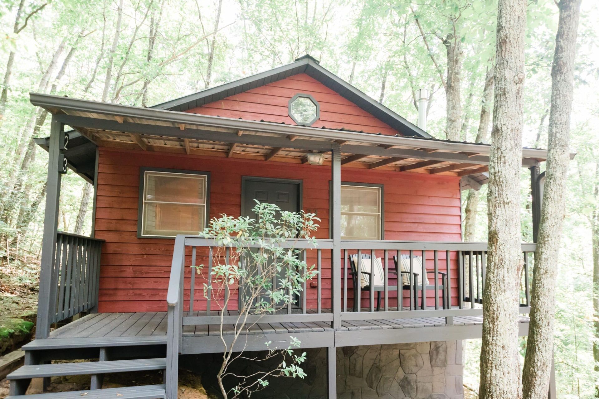 A small red house with a porch in the woods