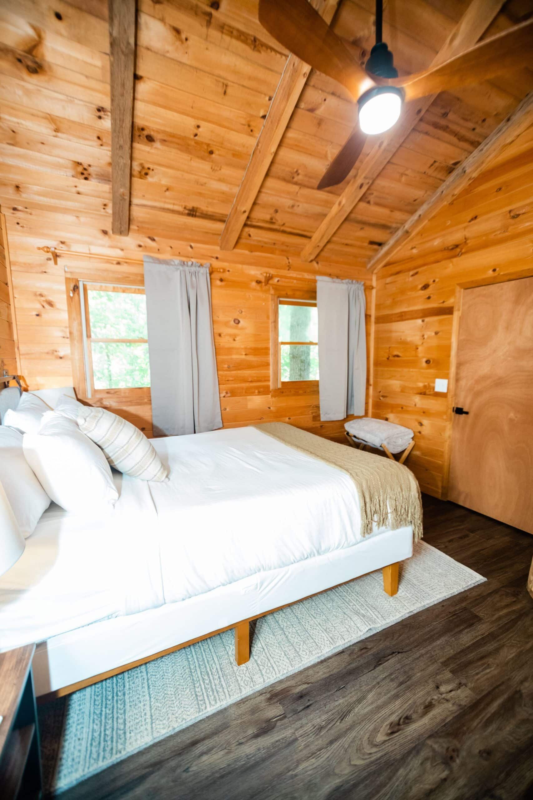 A bedroom in a log cabin with a bed and a ceiling fan.