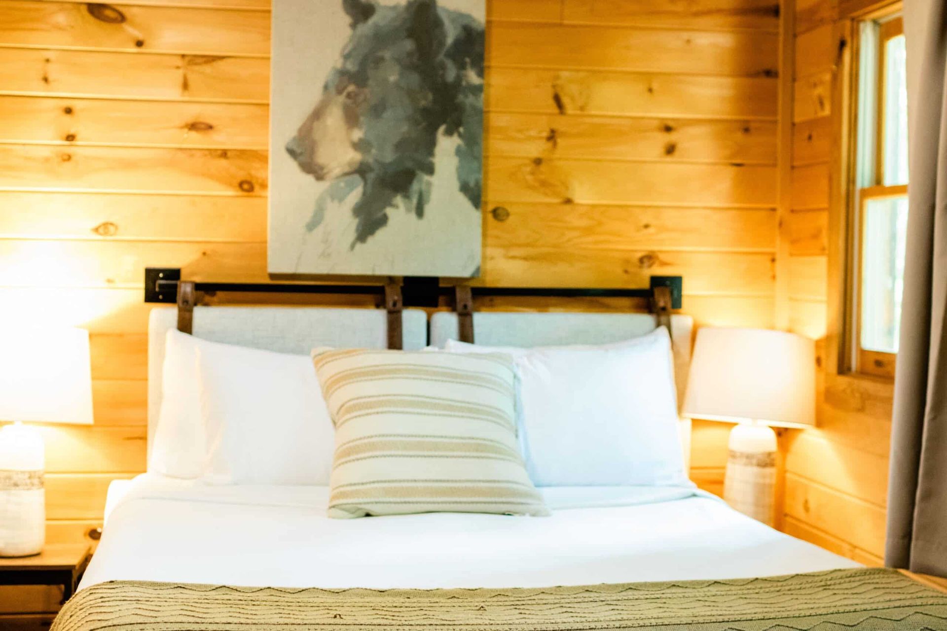 There is a painting of a bear on the wall above the bed.