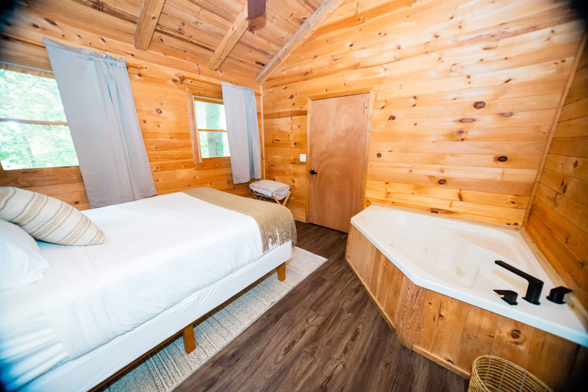 A bedroom in a log cabin with a bed and a jacuzzi tub.