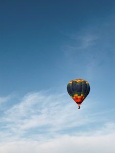 A colorful hot air balloon is flying in the blue sky.