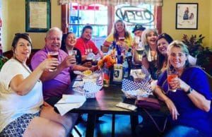 A group of people are sitting around a table holding drinks.
