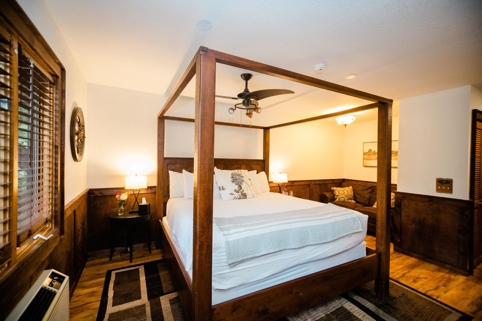 A bedroom with a four poster bed and a ceiling fan.