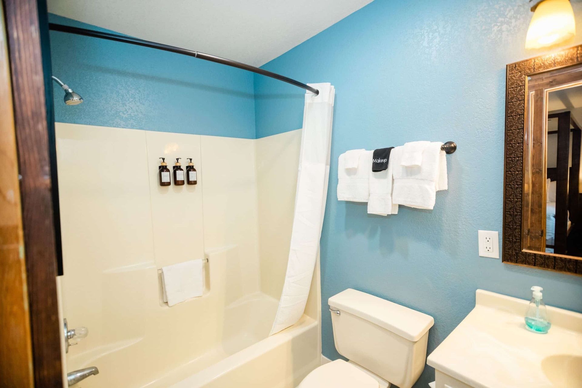 A bathroom with a toilet , sink , bathtub and mirror.
