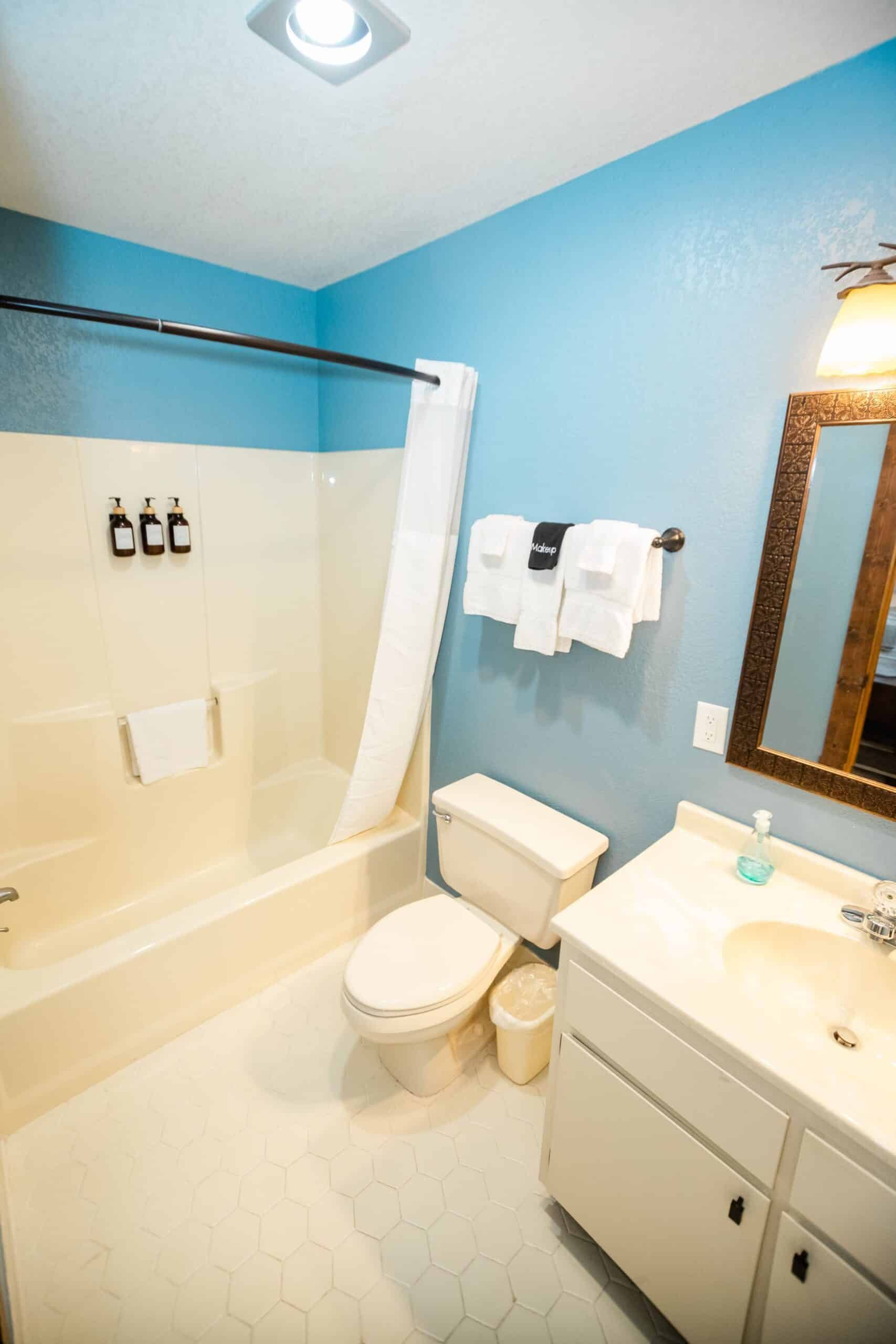 A bathroom with a toilet , sink , bathtub and mirror.