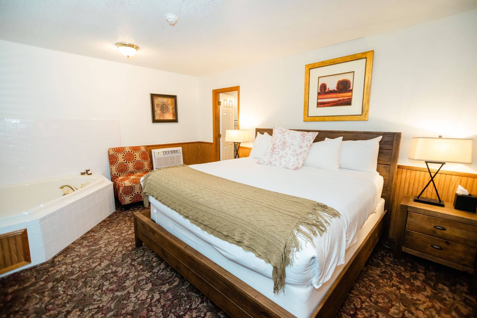 A hotel room with a king size bed and a jacuzzi tub.