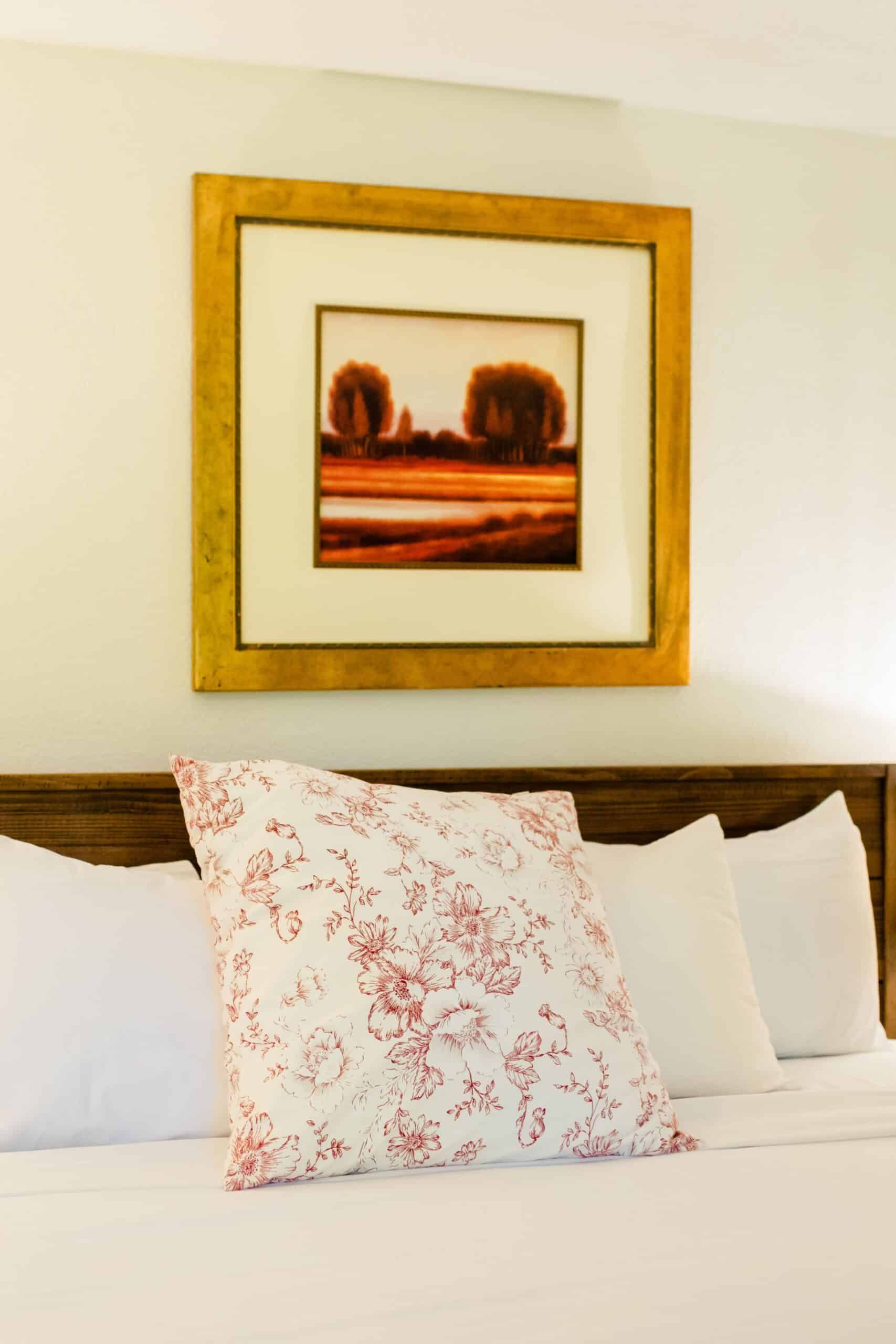 A bed with a picture on the wall above it