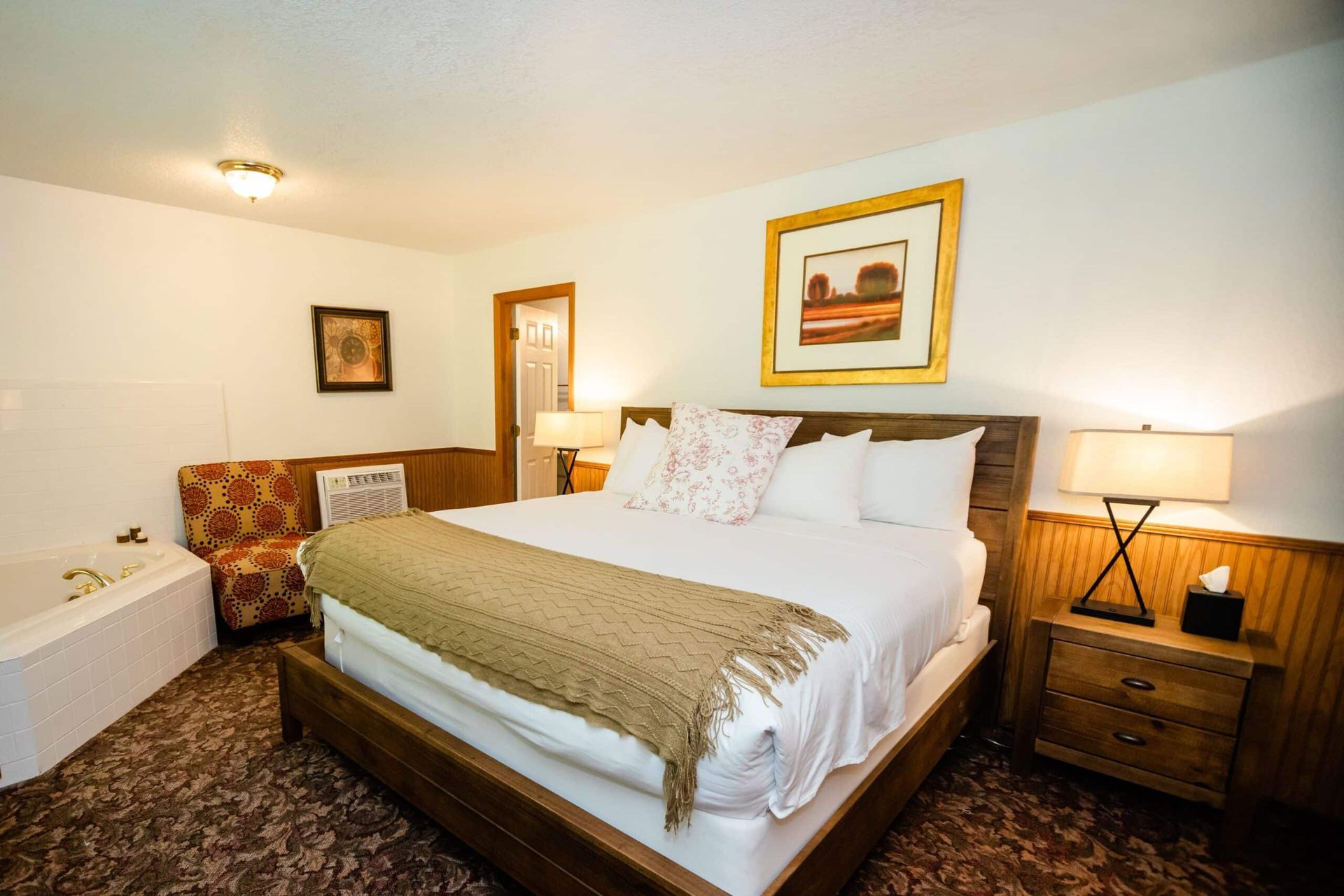 A hotel room with a king size bed and a jacuzzi tub.