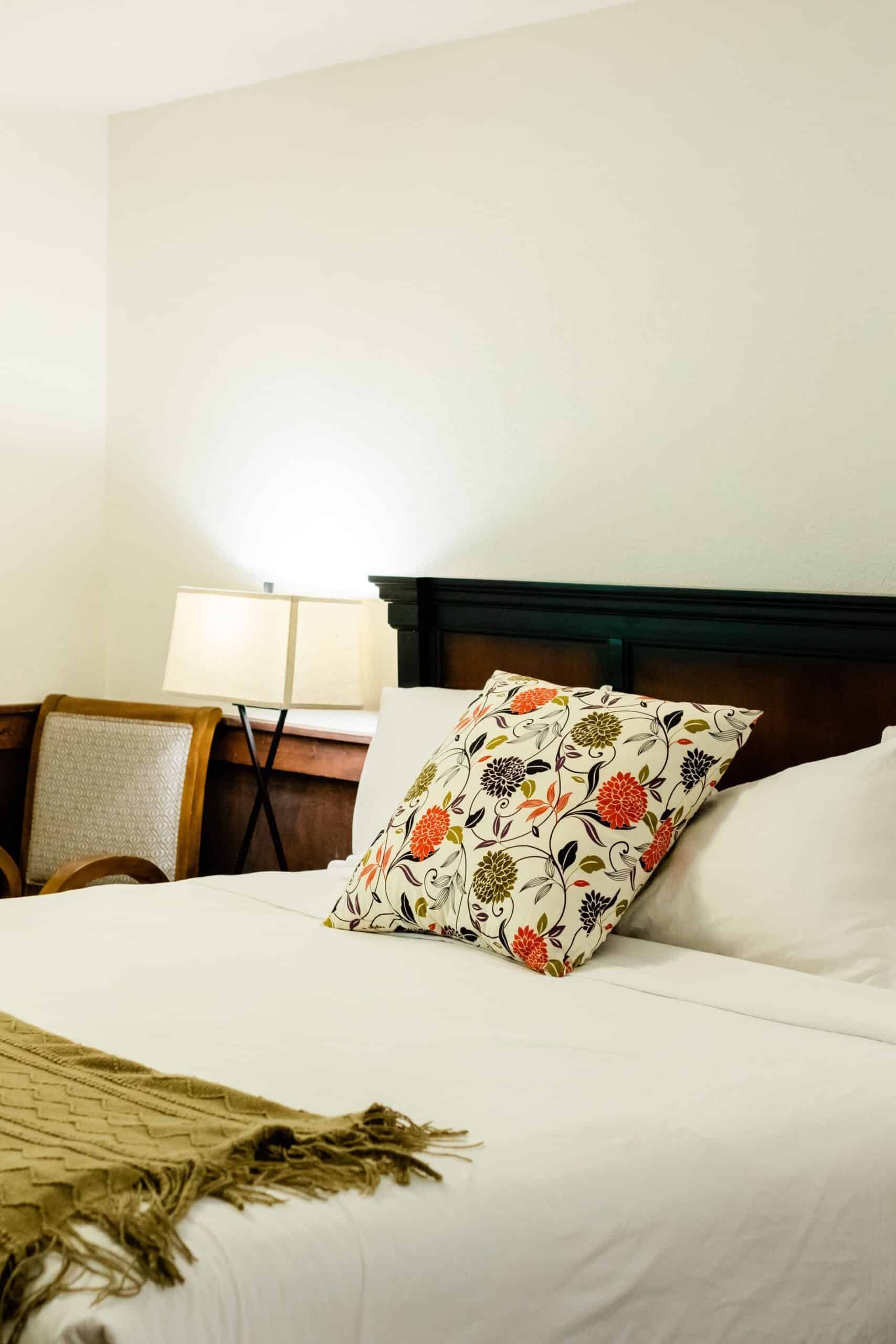A bed with a floral pillow on it in a hotel room.