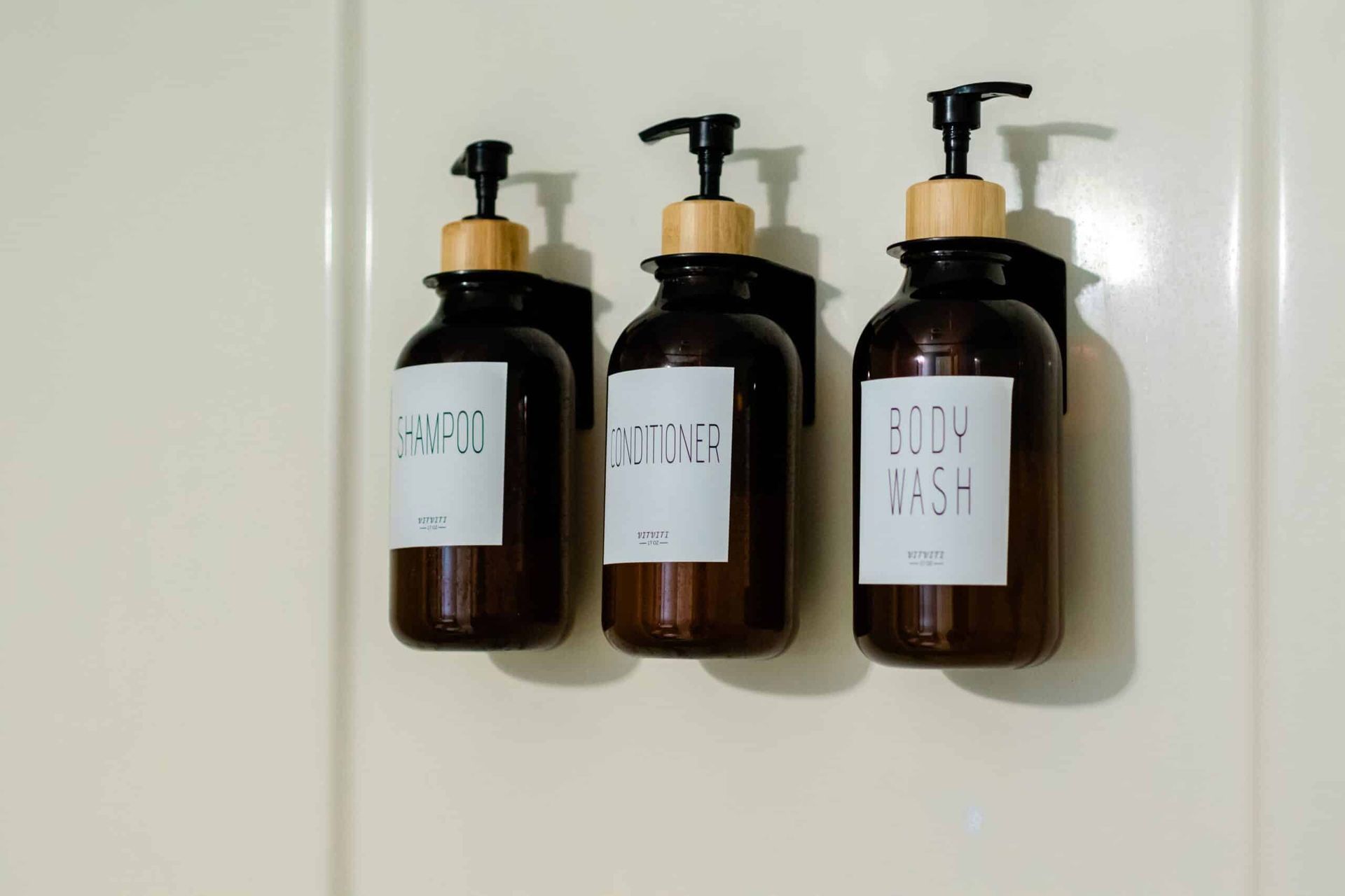 Three bottles of soap are hanging on a wall.