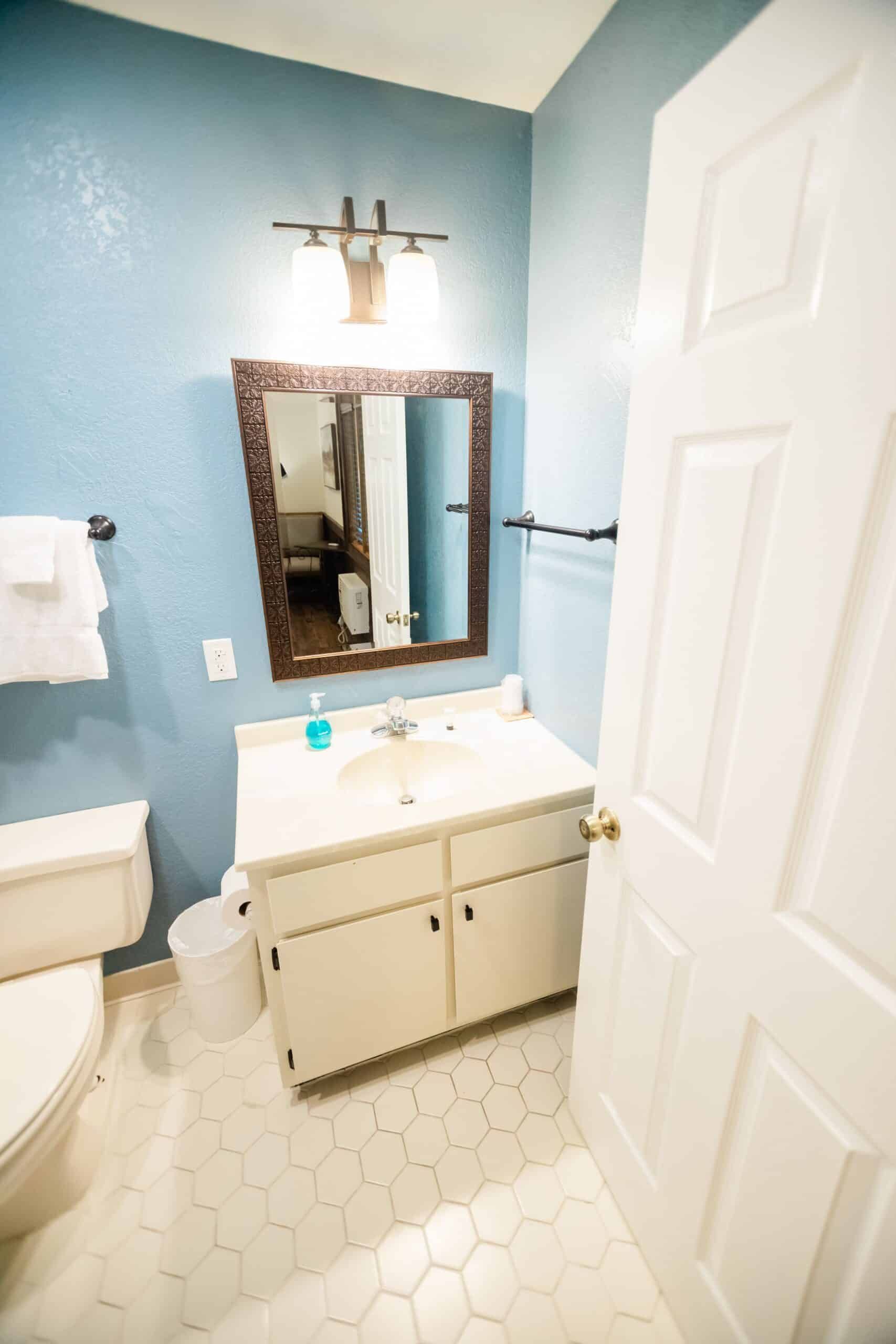 A bathroom with a sink , toilet , mirror and blue walls.