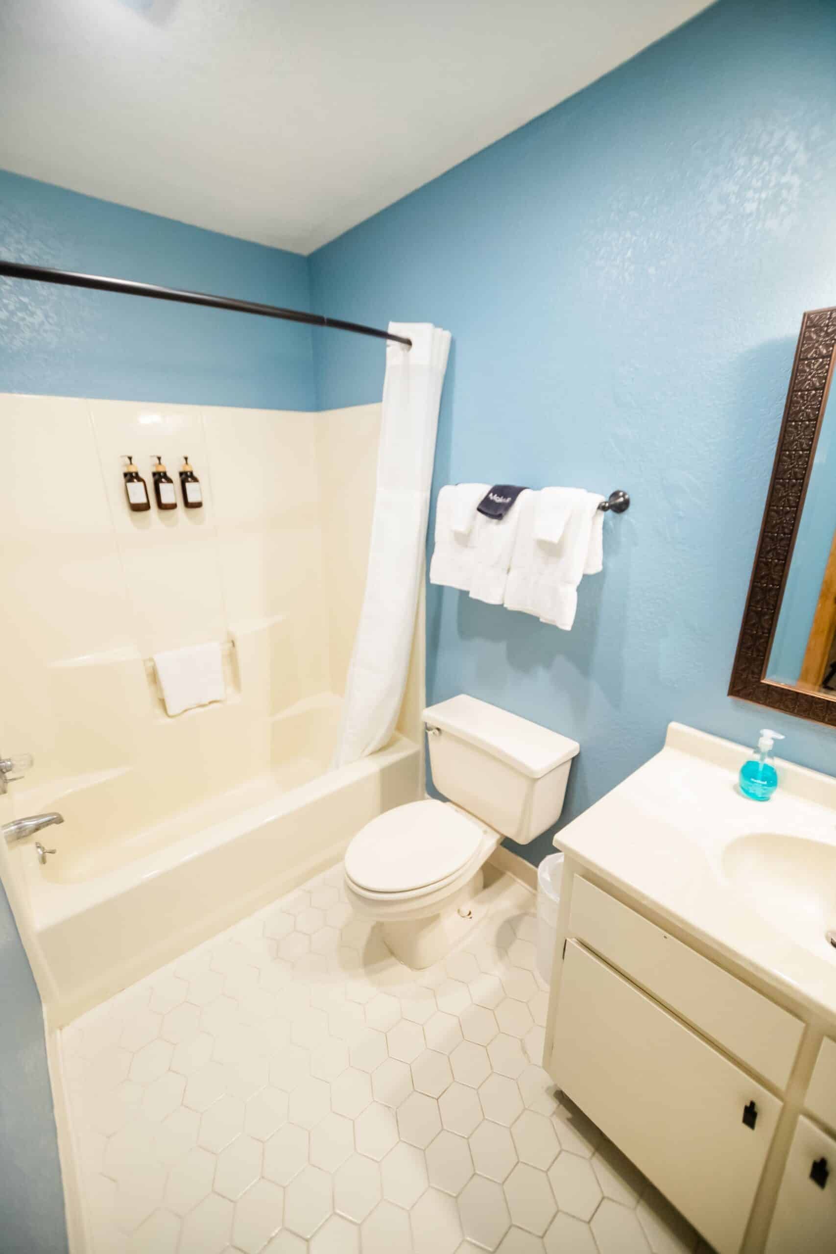 A bathroom with a toilet , sink , bathtub and mirror.