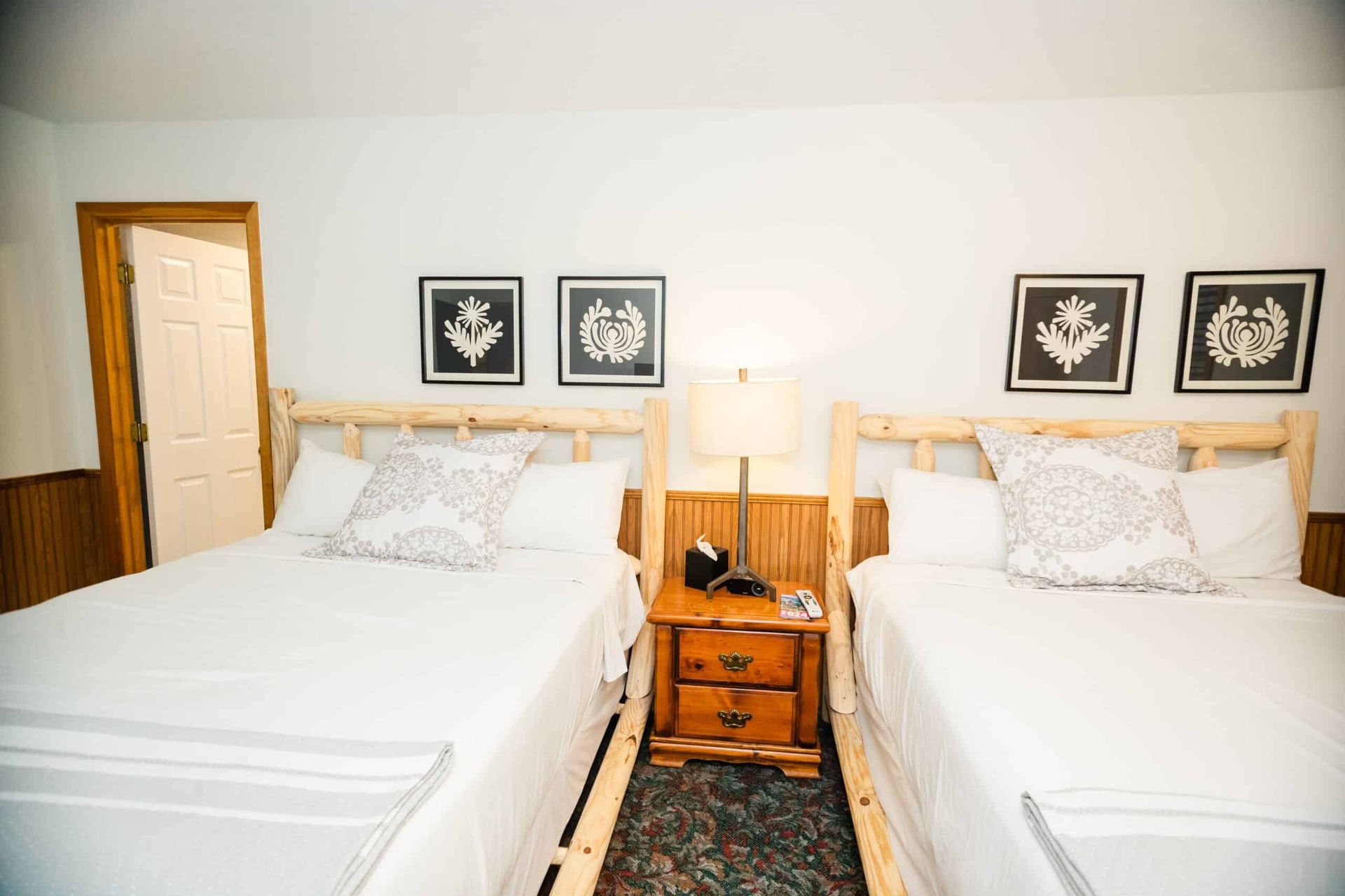 A bedroom with two beds and a nightstand.