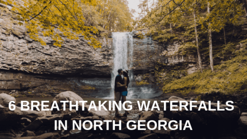 A couple is standing in front of a waterfall in north georgia.