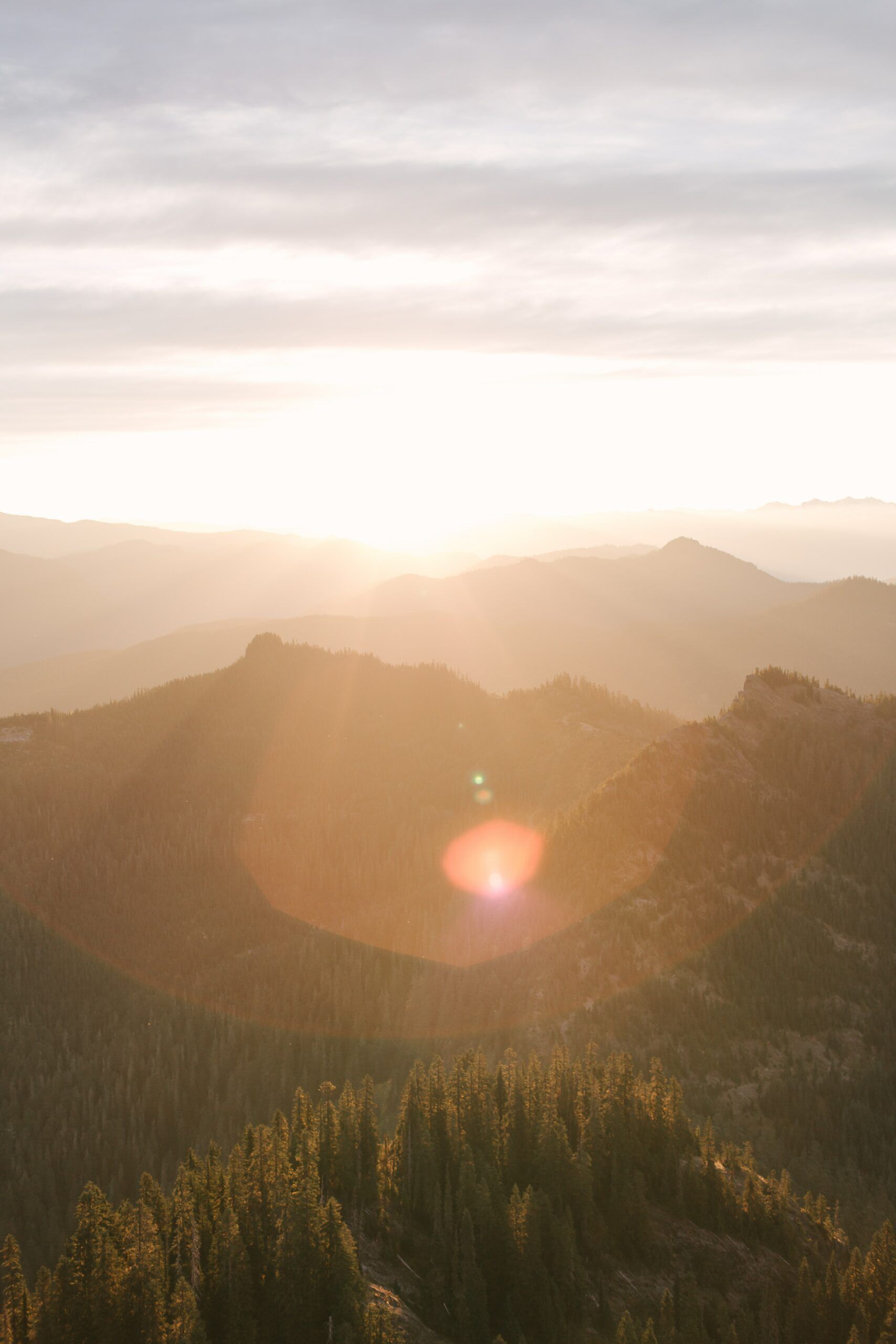 The sun is shining through the clouds over the mountains.