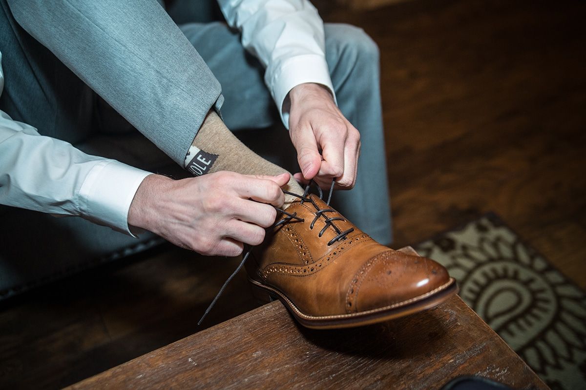 A man is tying his shoes on a wooden table.