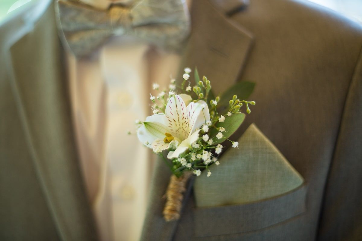 A man in a suit and bow tie has a flower in his pocket.
