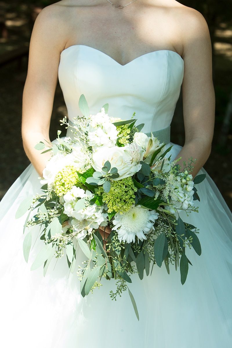A bride and groom are kissing in the woods.