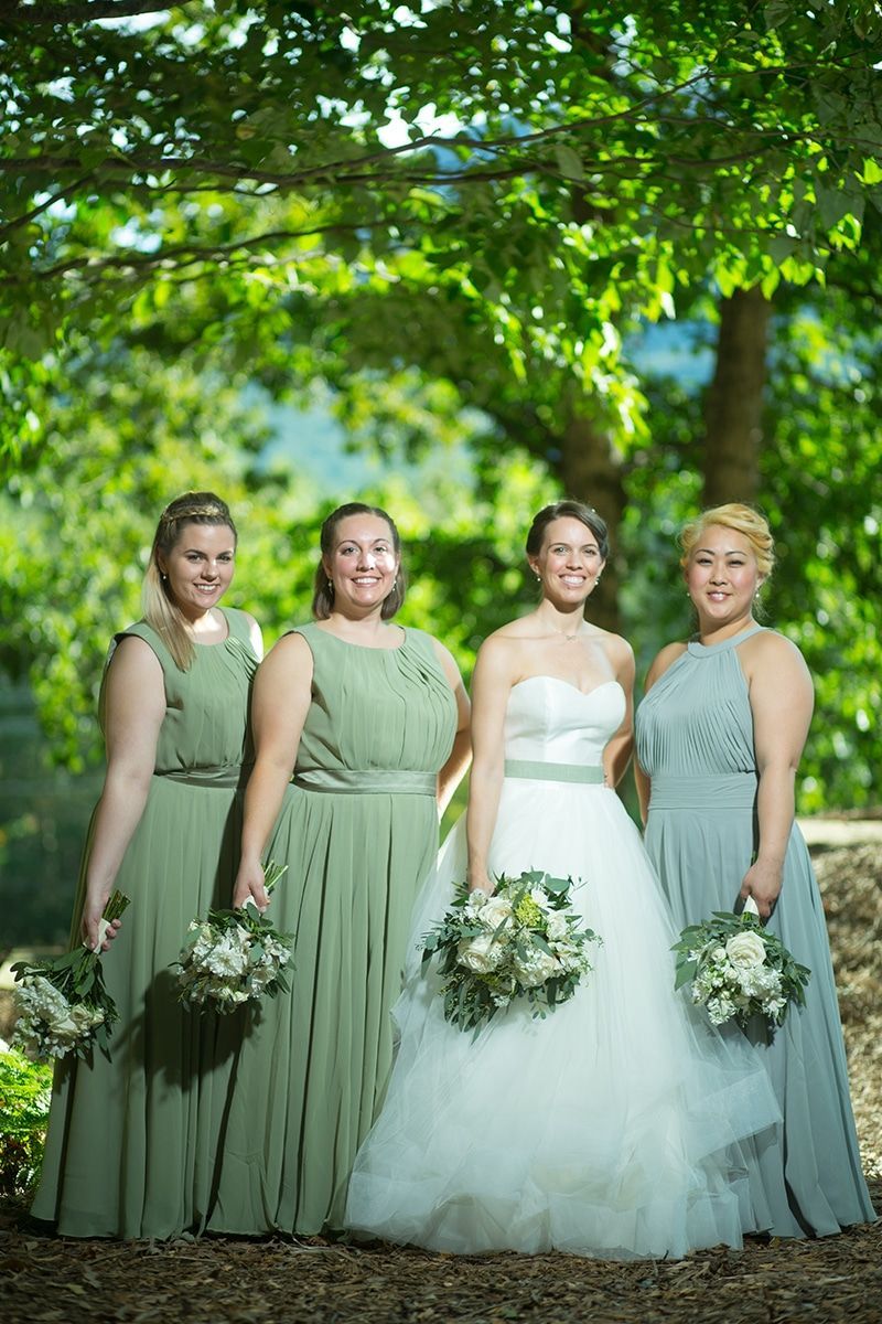 A bride and her bridesmaids are posing for a picture in front of a tree.