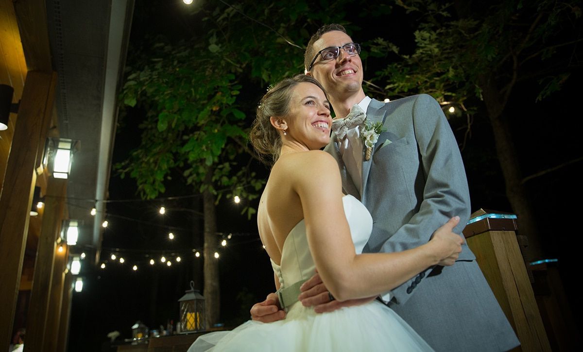 A bride and groom are posing for a picture at their wedding reception.