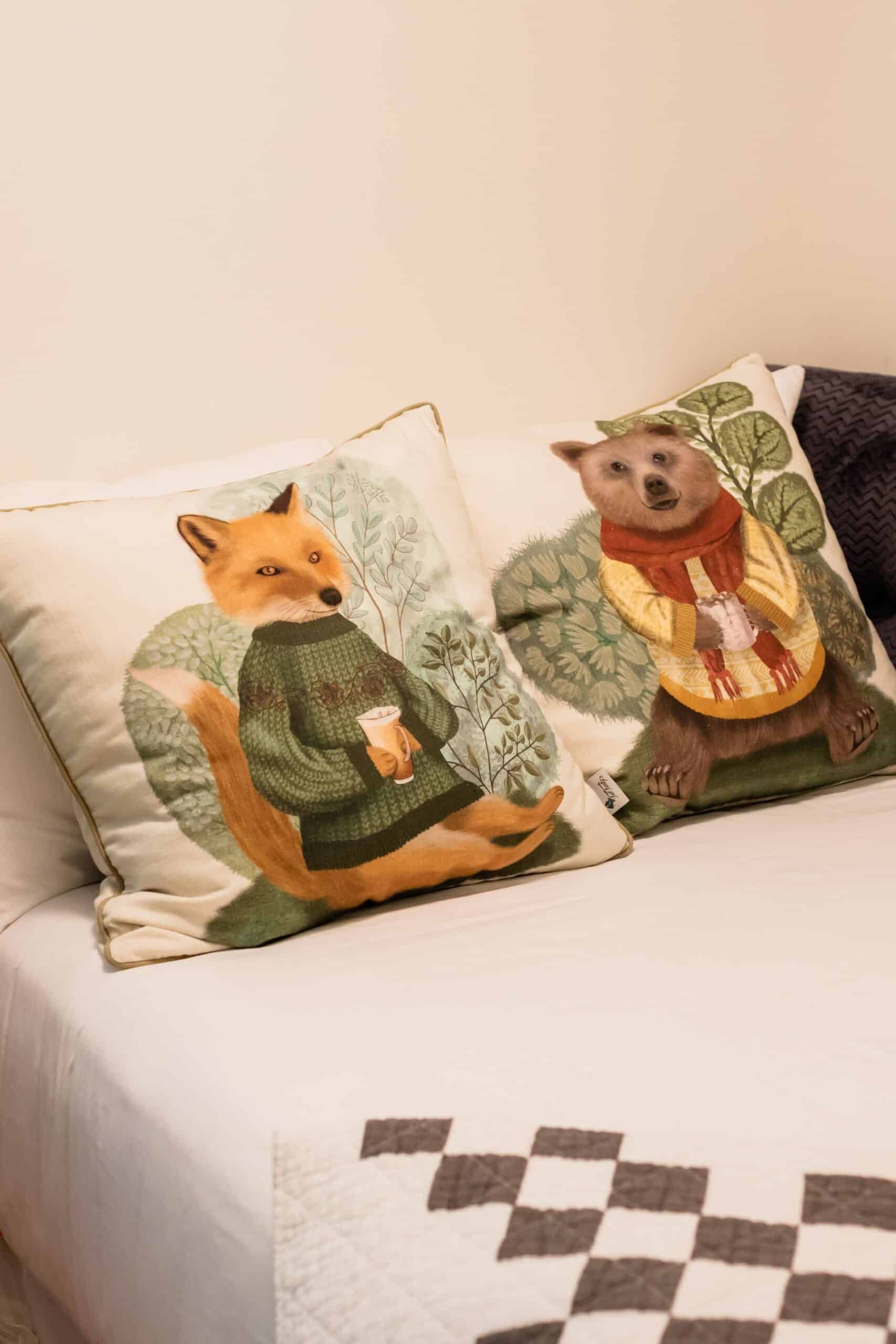 A fox and a bear pillow are sitting on a bed.