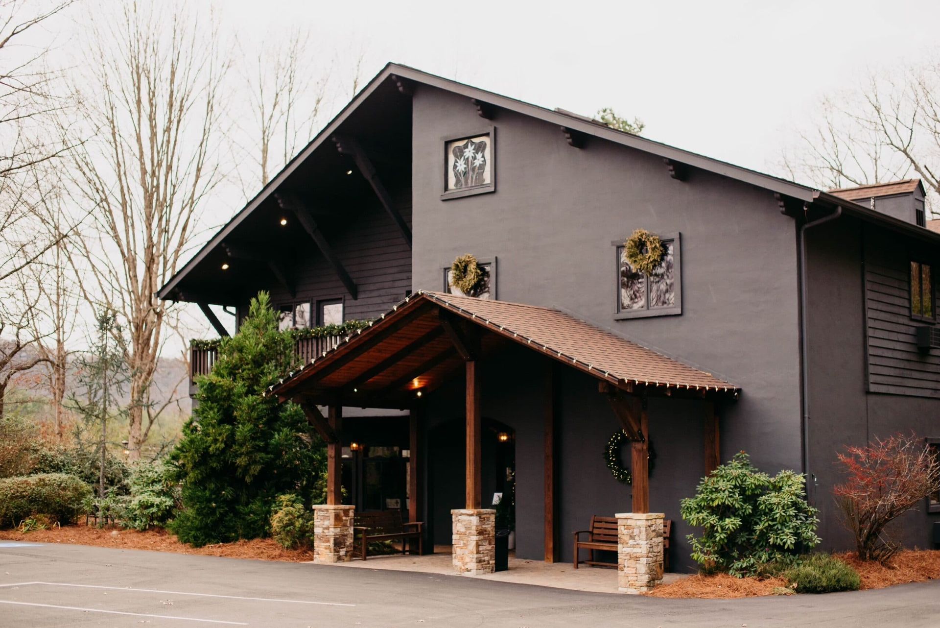 A large black building with a porch and trees in front of it.