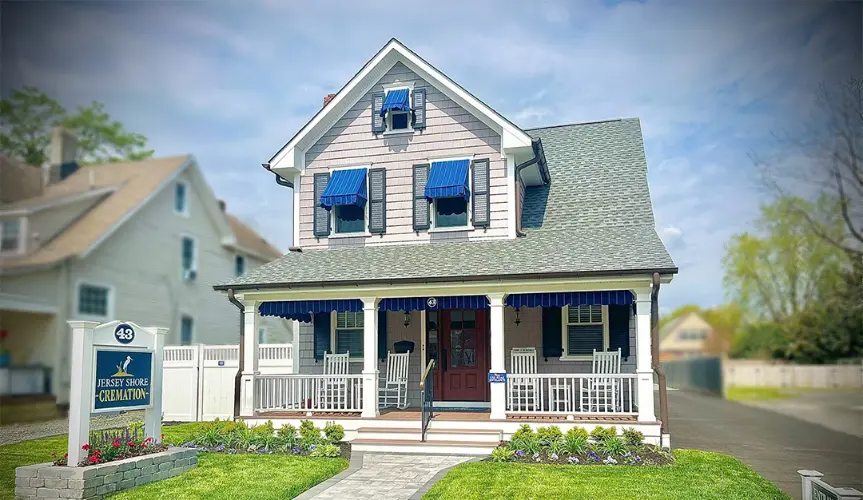The front door of a house with a porch and plants in front of it.