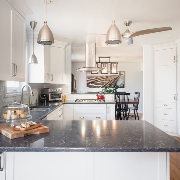 A kitchen with white cabinets and a black counter top