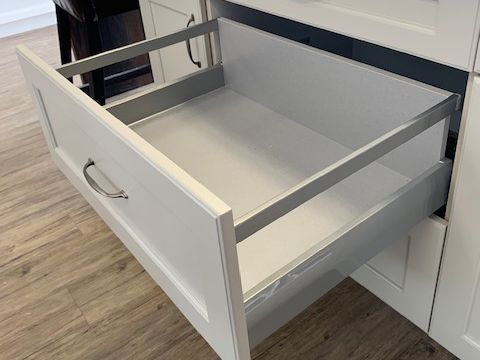 A white drawer with a metal frame is open in a kitchen.