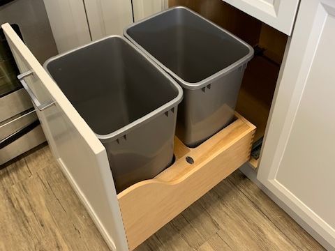 Two trash cans are pulled out of a drawer in a kitchen.