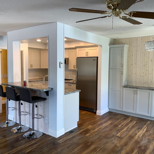 A kitchen with stools and a ceiling fan