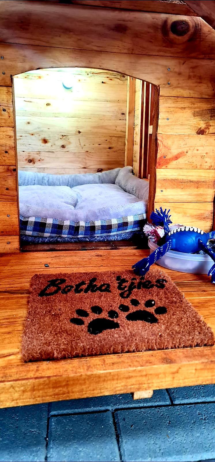 A wooden dog house with a door mat and a bed.