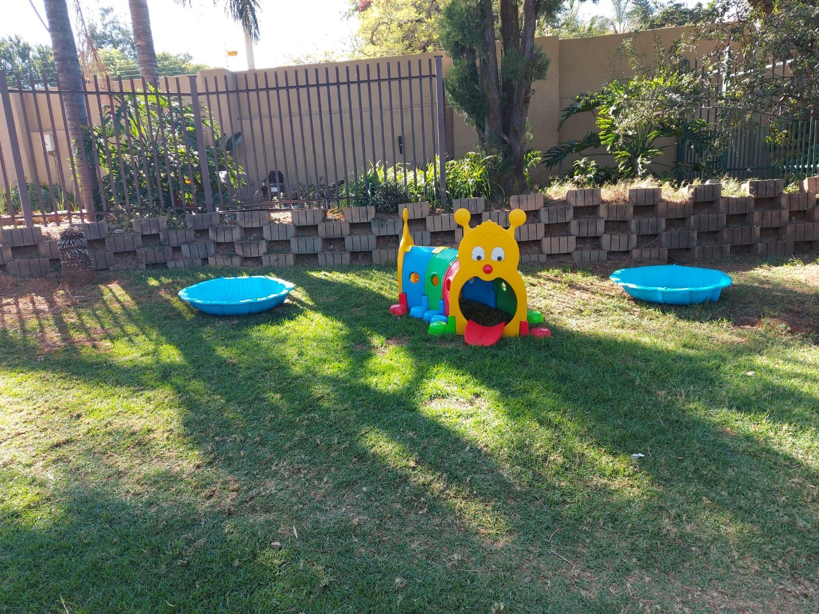 A colorful toy caterpillar is sitting in the grass in a yard.