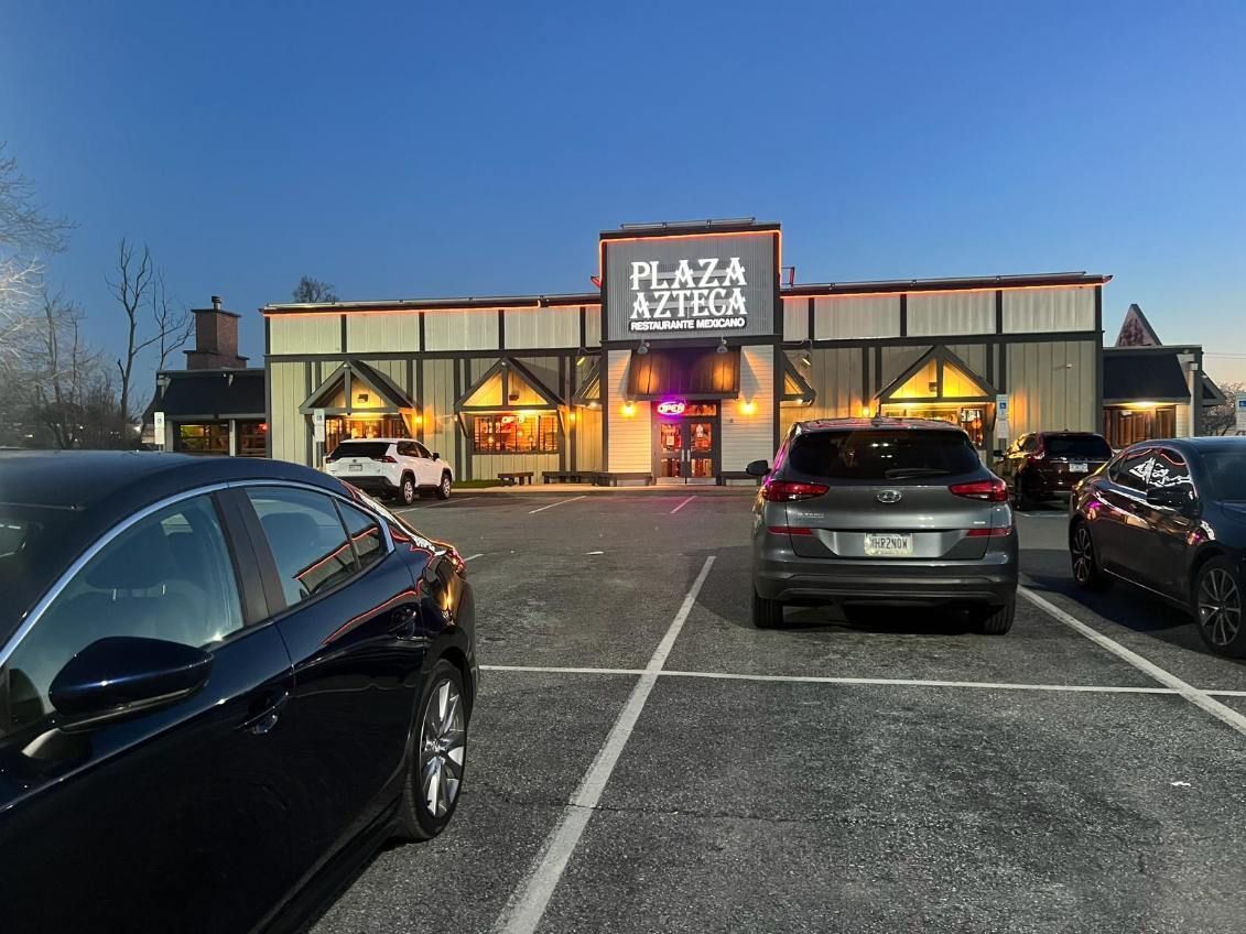 A parking lot with cars parked in front of a restaurant called plaza pizza.