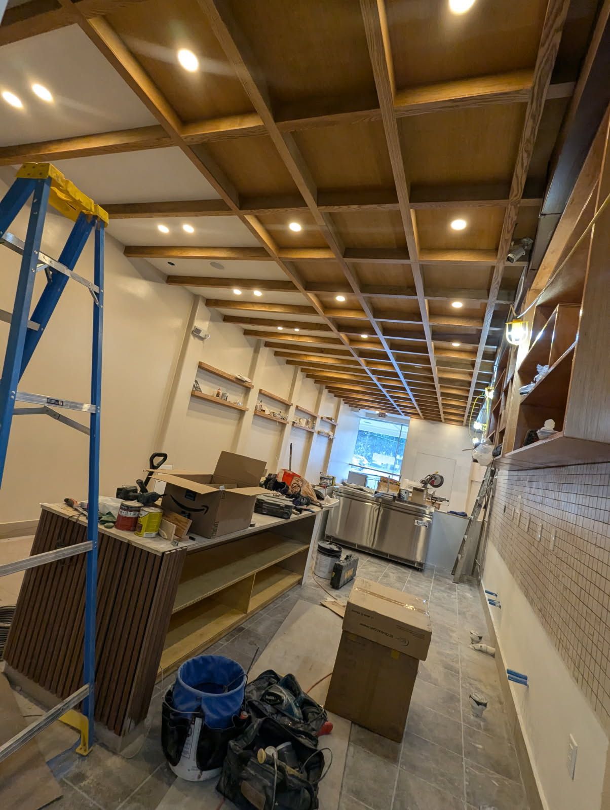 A large room with a wooden ceiling and a ladder.