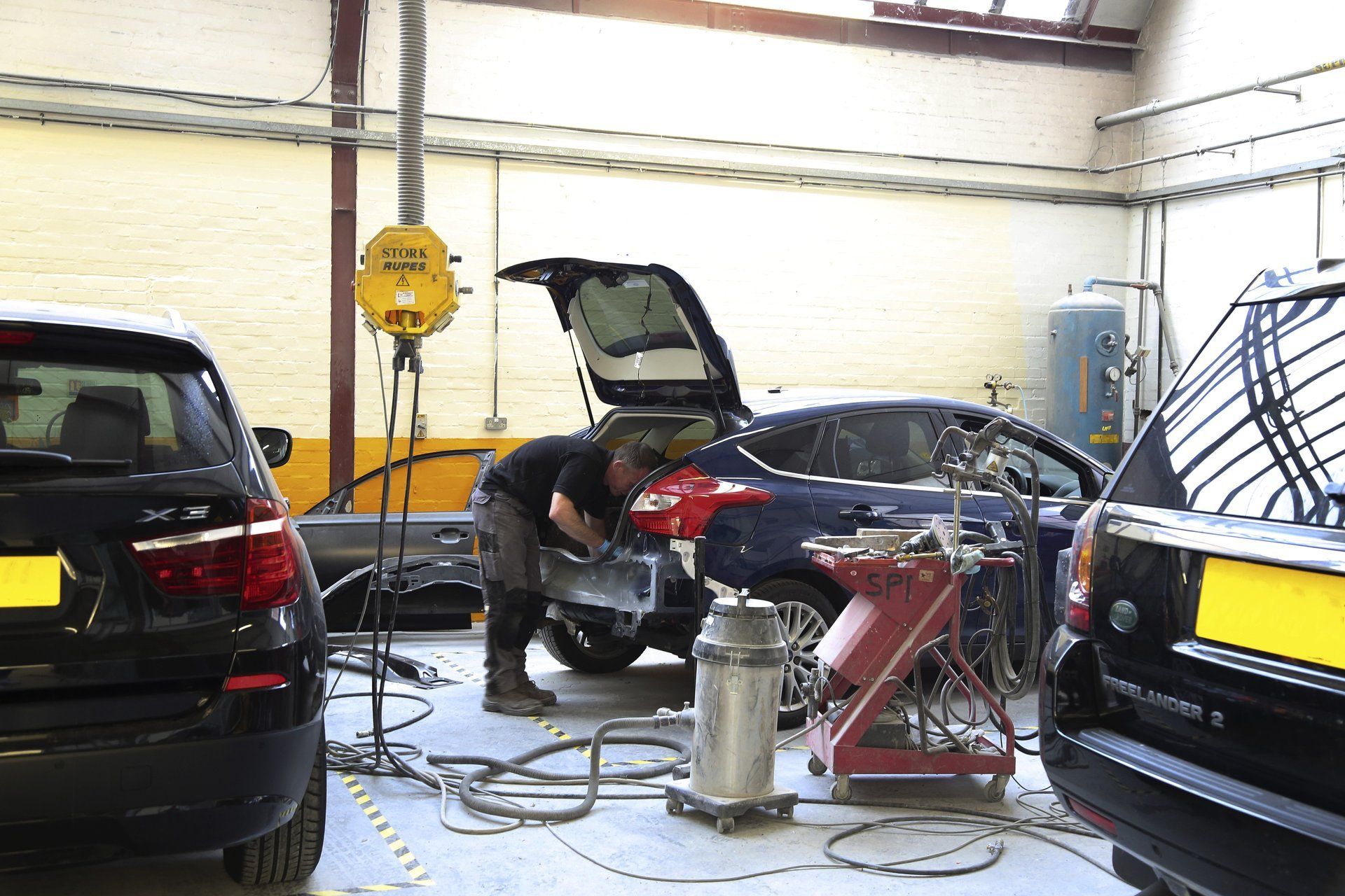 A man is working on a car in a garage.