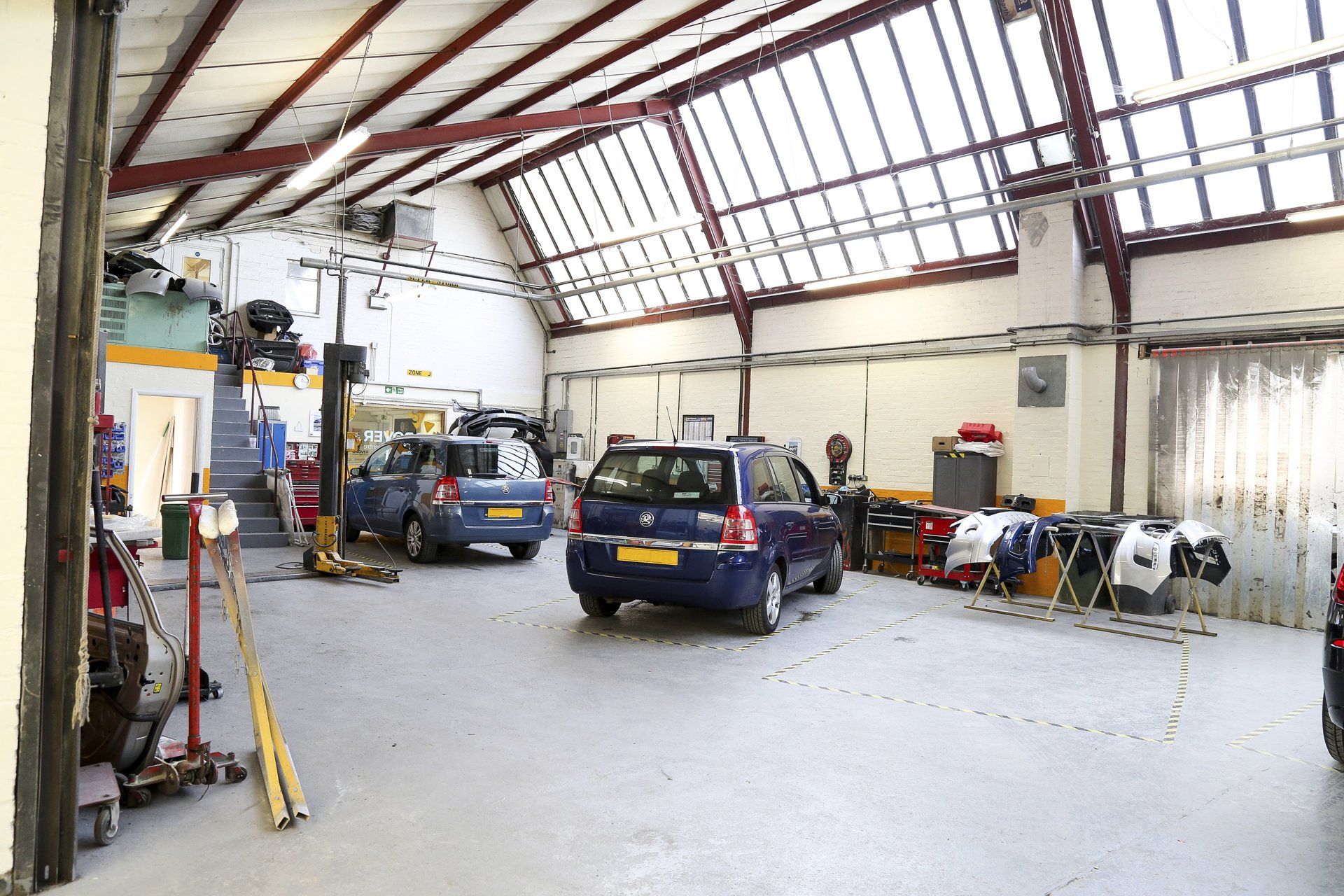 A blue car is parked in a garage with other cars