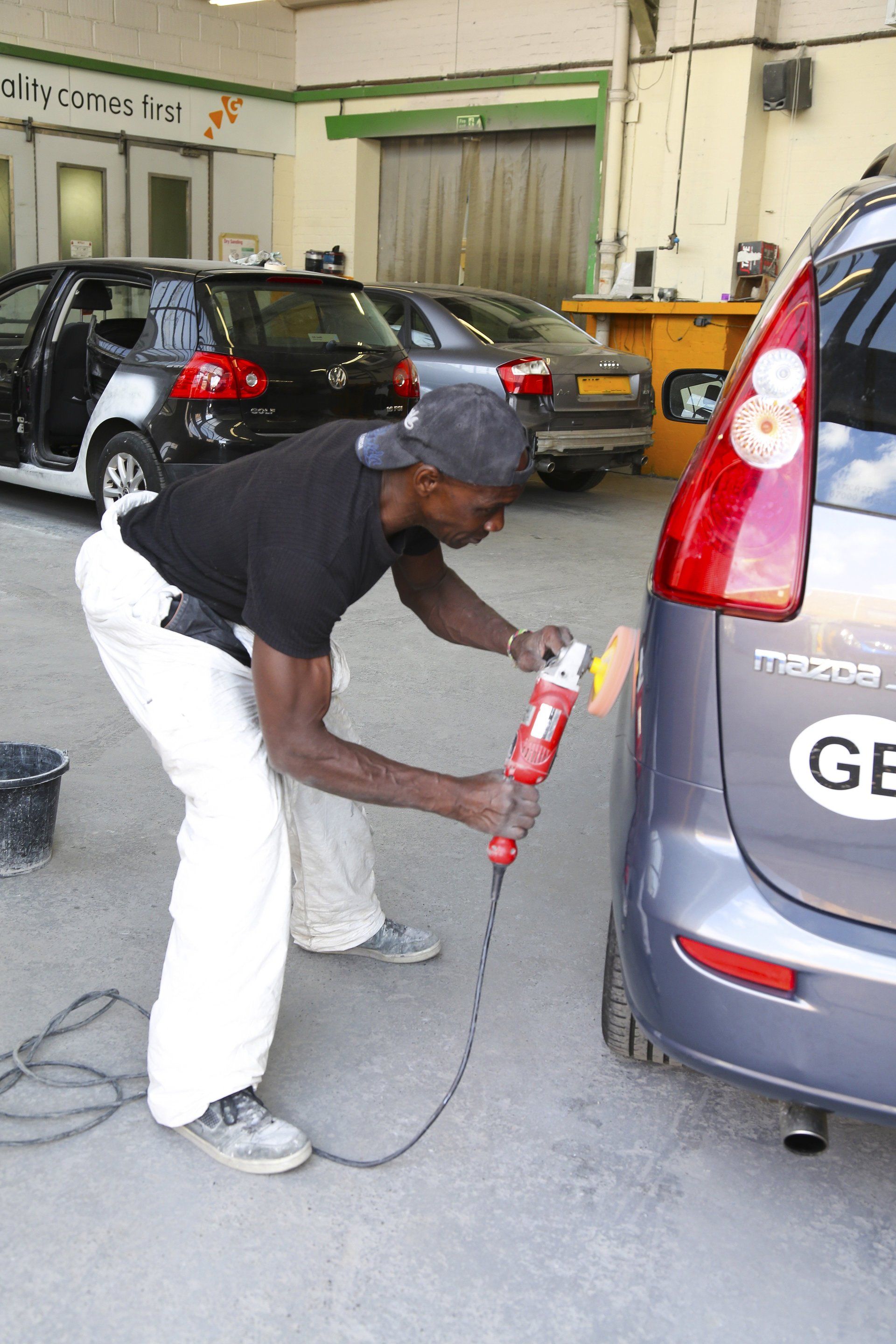 A man is polishing a car with a license plate that says ge