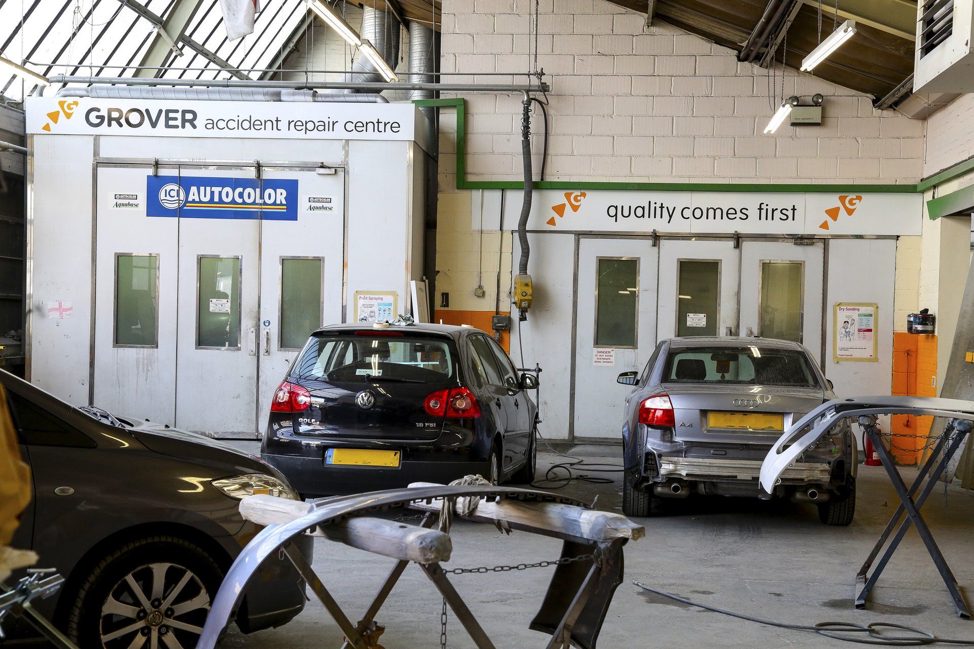 Two cars are parked in a garage with a sign that says grover on it.