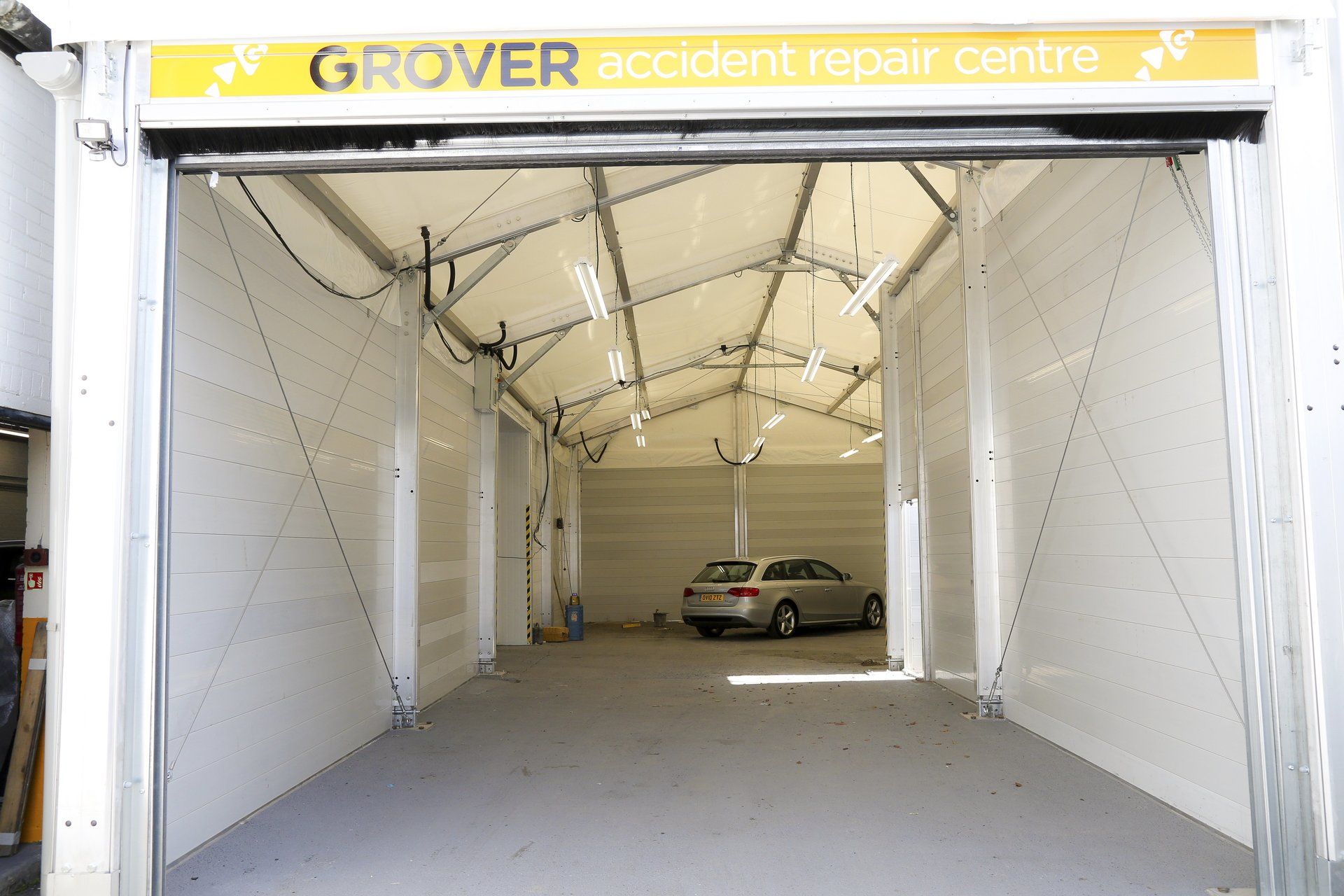 A car is parked inside of a garage that says grover accident repair centre