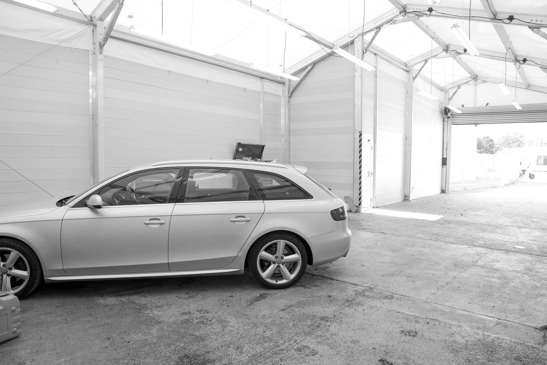 A silver car is parked in a garage in a black and white photo.