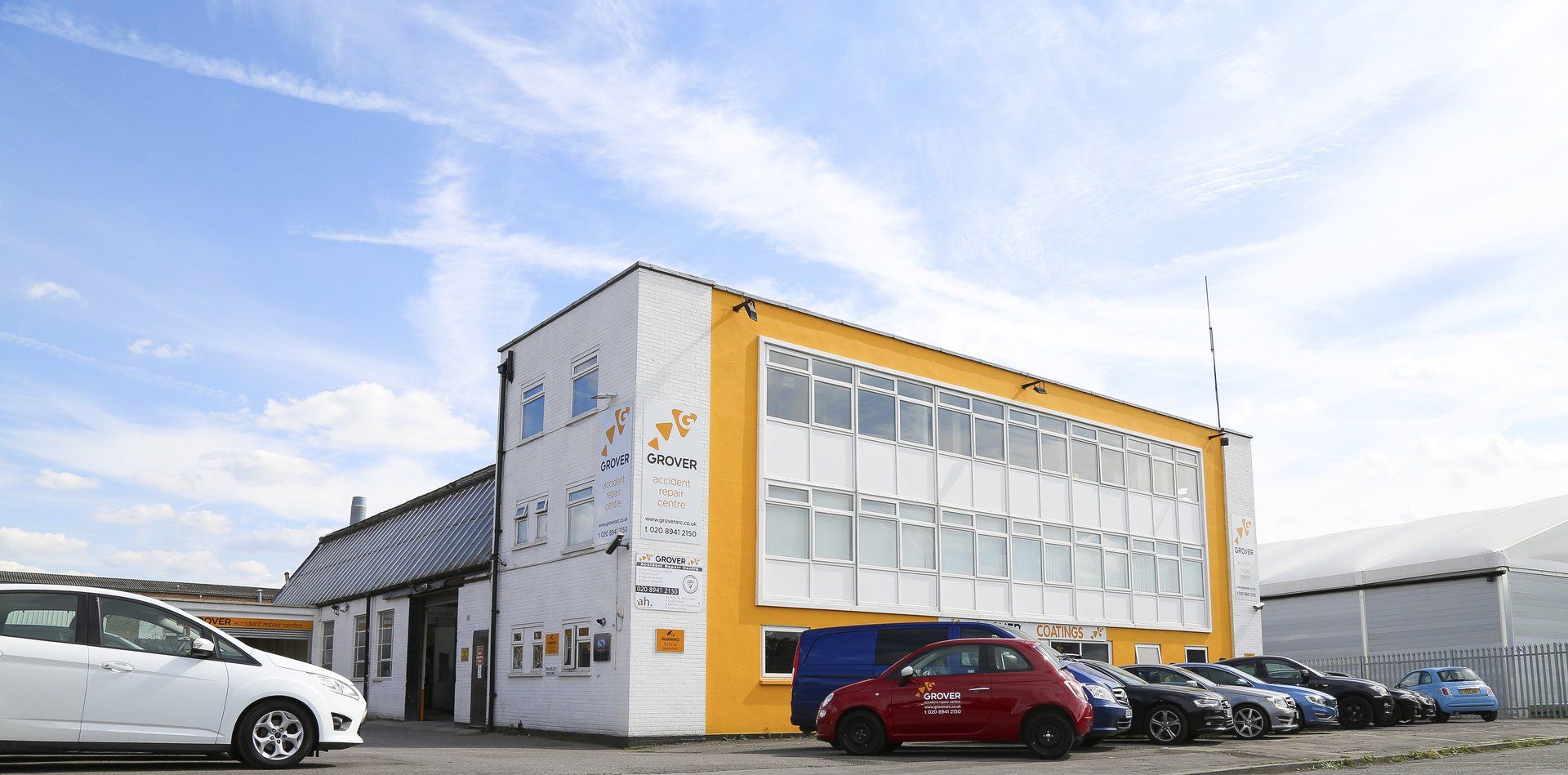 A row of cars are parked in front of a large building.