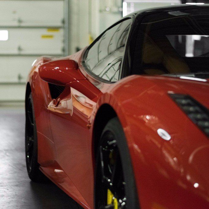 A red sports car is parked in a garage