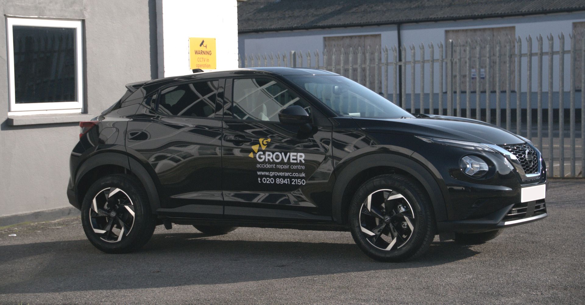 A black car is parked in front of a building.