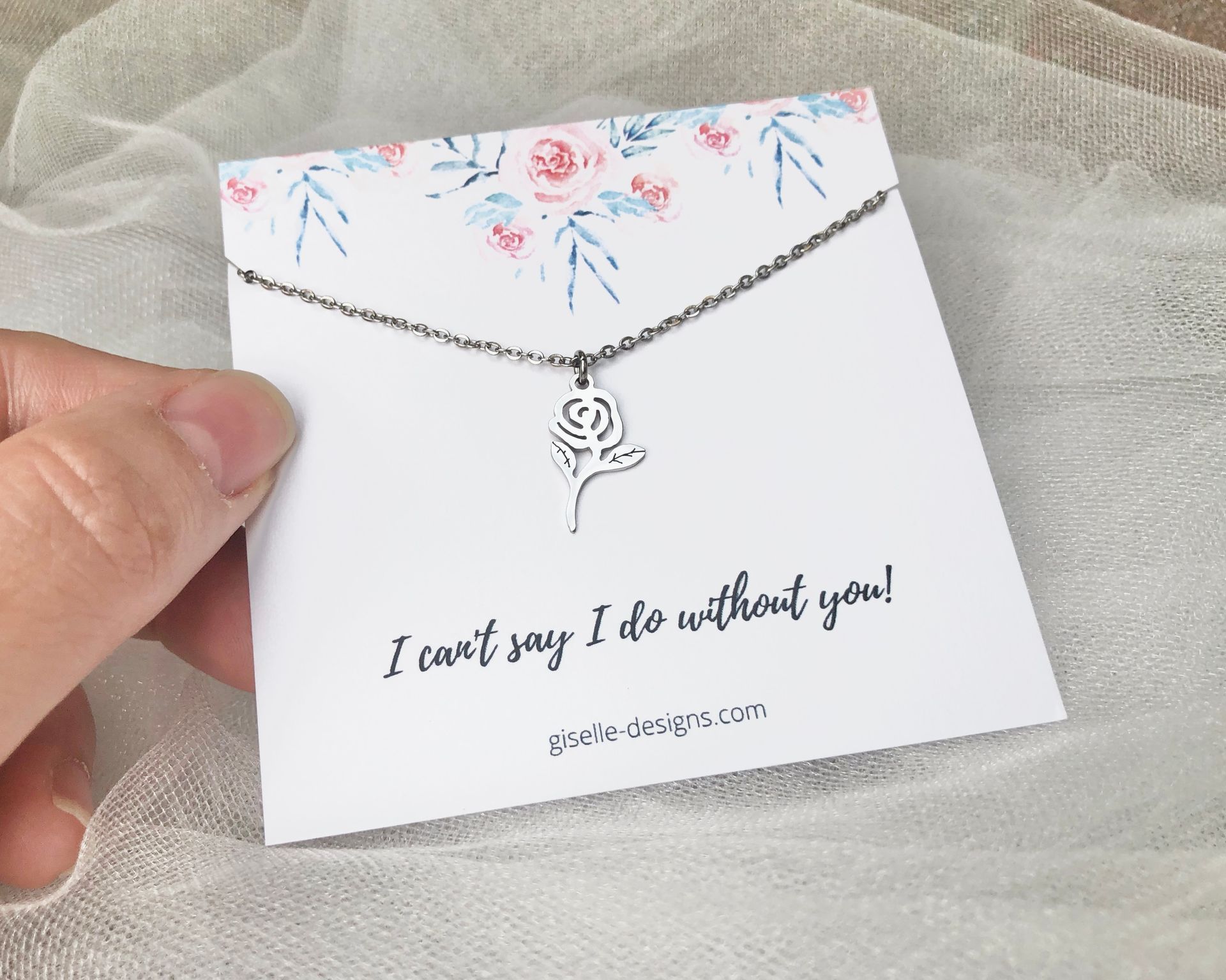 Hand holding a card with a silver lotus flower necklace. Card reads 