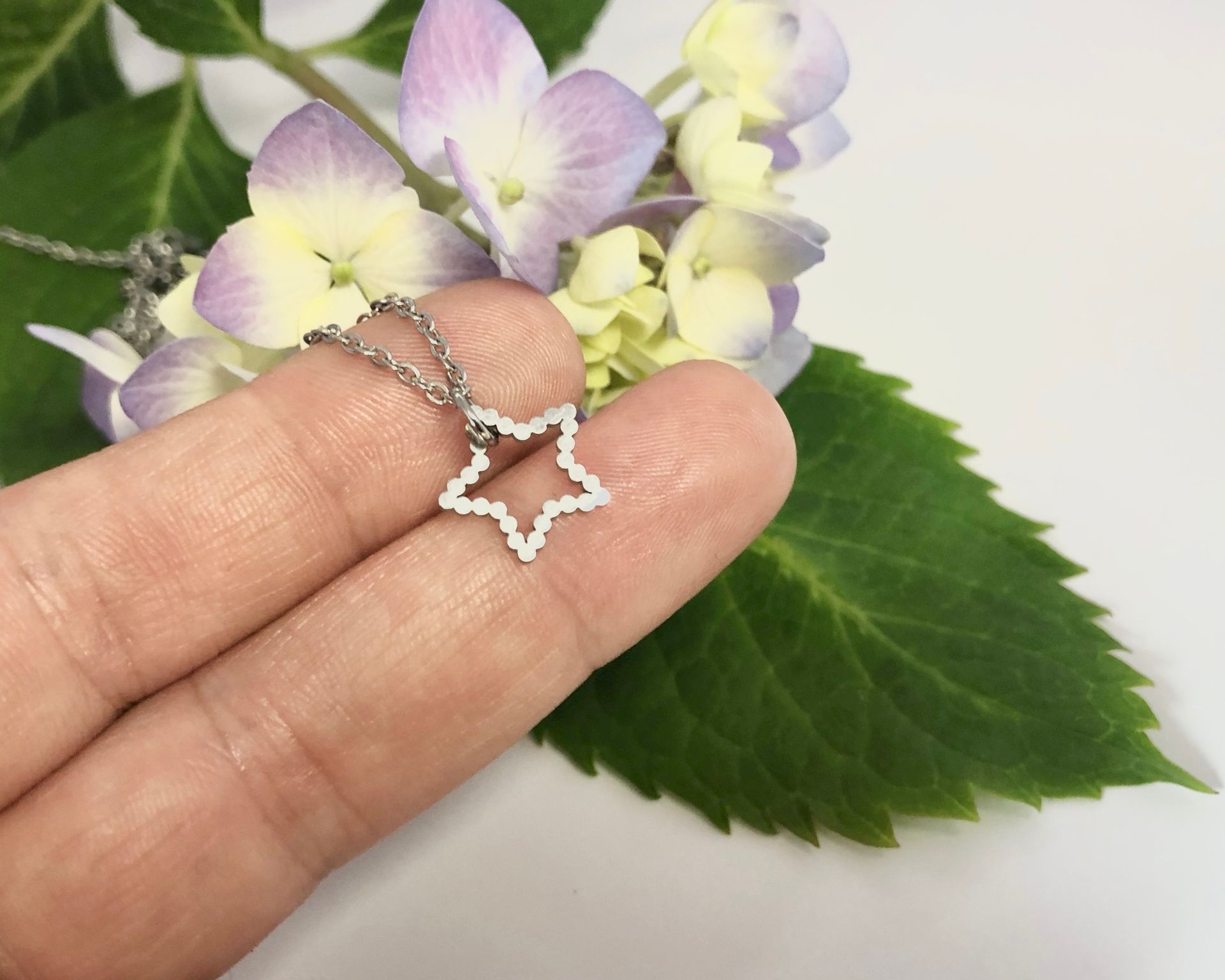 Hand holding a card with star necklace. Text reads, 