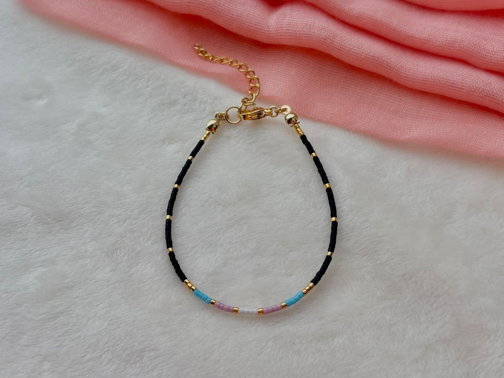 Black beaded bracelet with gold accents, blue, pink, and gold beads.