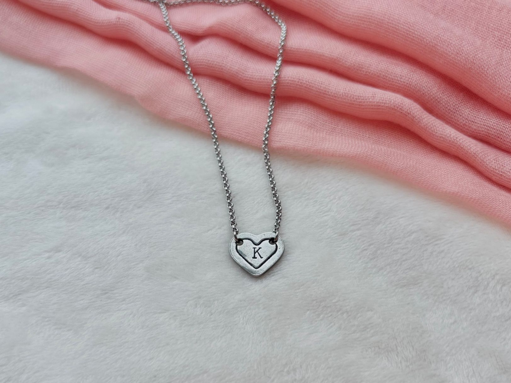 Silver necklace with a heart-shaped pendant, featuring the letter 